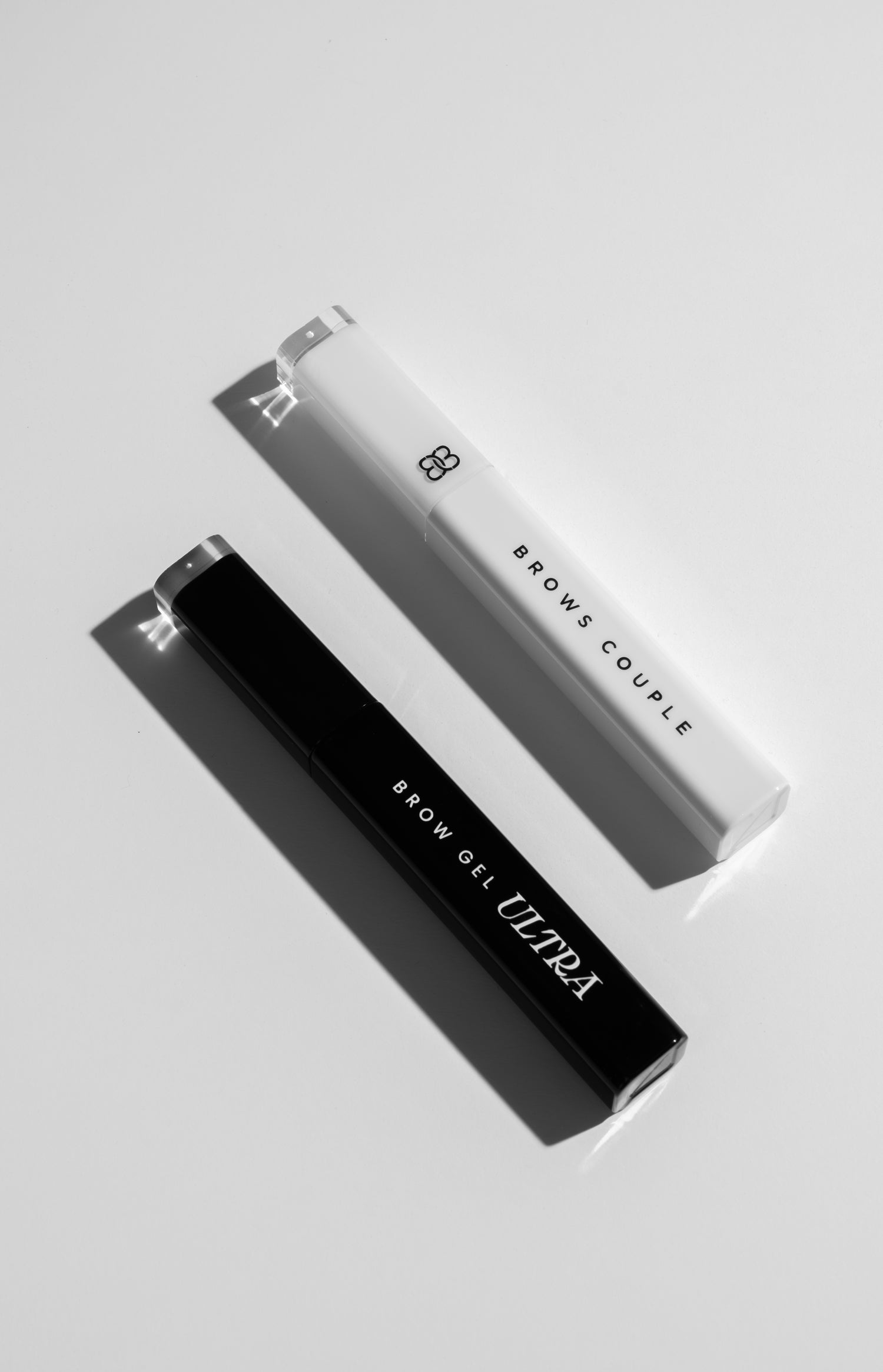 Two eyebrow gel bottles, on a light gray background.